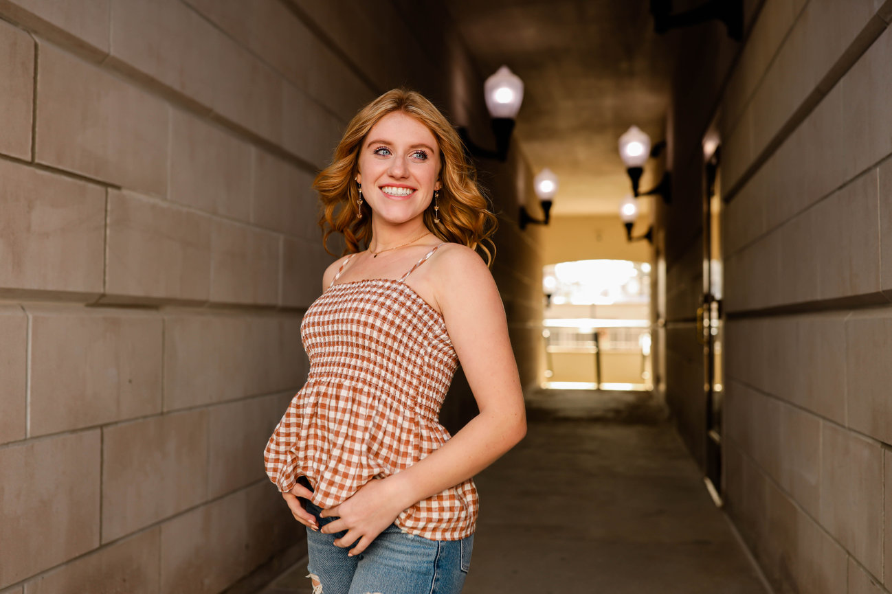 Teen girl smiling and standing in outdoor alley during senior photo shoot in Farmington, MI