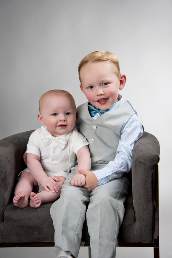 Two little boys posing for a portrait in a studio.