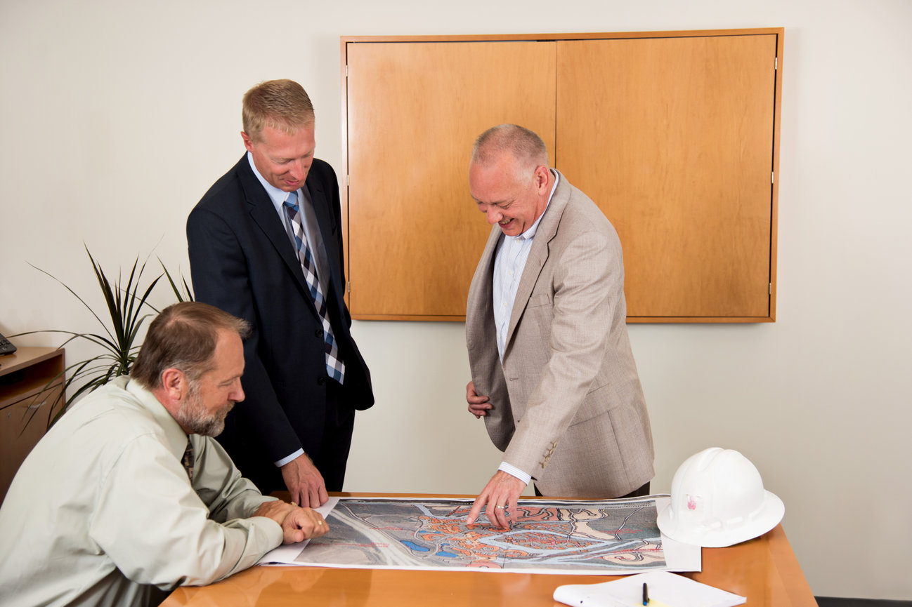 Team of 3 construction attorneys looking over some plans.