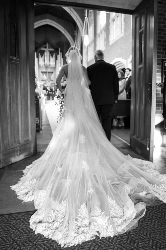Black and white image of bride in lace Olia Zavozina wedding gown walking down the aisle with her father at Scarritt Bennett. Nashville wedding photography by Heather Durham.