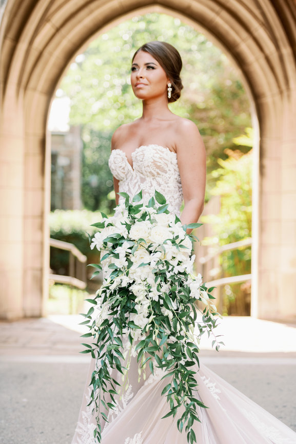Beautiful bride in blush Olia Zavozina wedding dress holding cascading bridal bouquet in shades of white with greenery. Nashville wedding photography by Heather Durham.