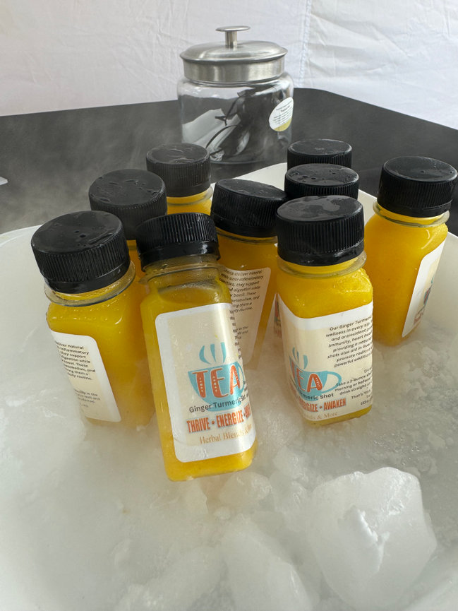 Small bottles of ginger turmeric juice are displayed on ice, with a jar in the background.