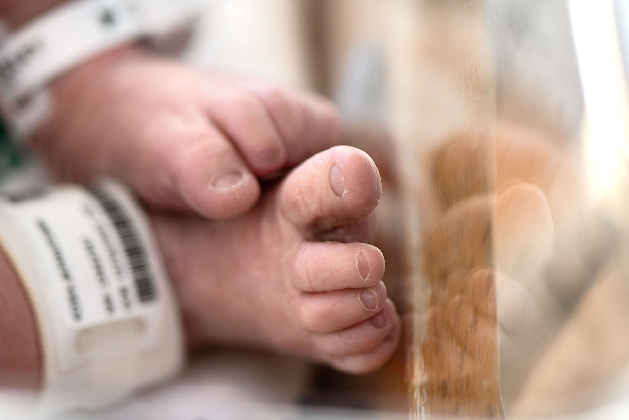 Close-up of a newborns feet resting on a soft surface at Advocate Good Shepherd Hospital. The baby wears an identification band around the ankle. The image captures tiny toes and delicate skin, conveying a sense of new life and fragility.