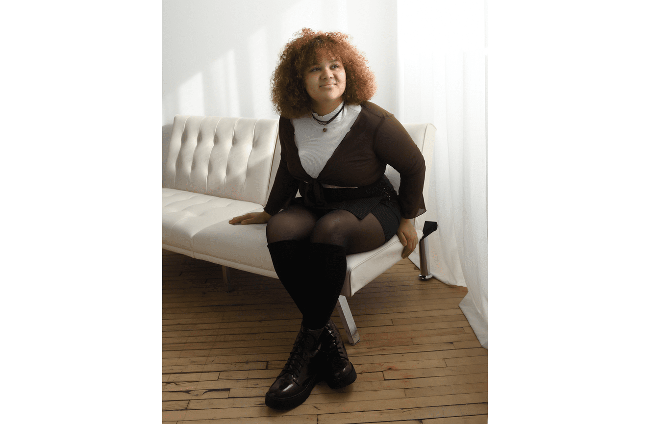 An African American young woman wearing Doc Martin boots looking out the window.