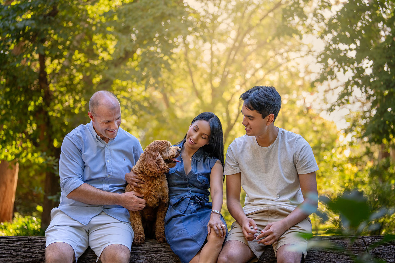 Photography of 3 people sitting on a log looking at their dog