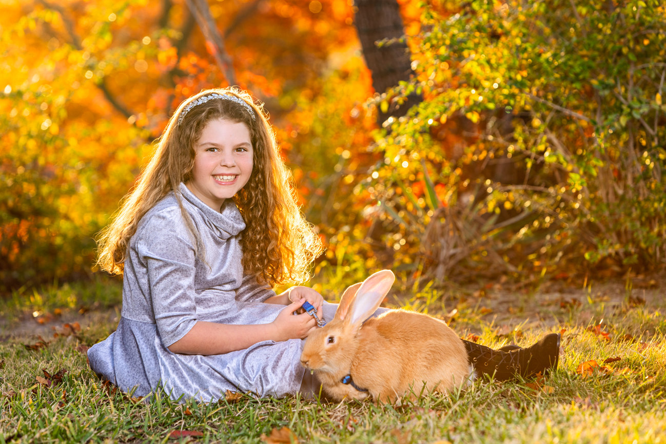 Portrait of a child with her pet bunny at sunset.