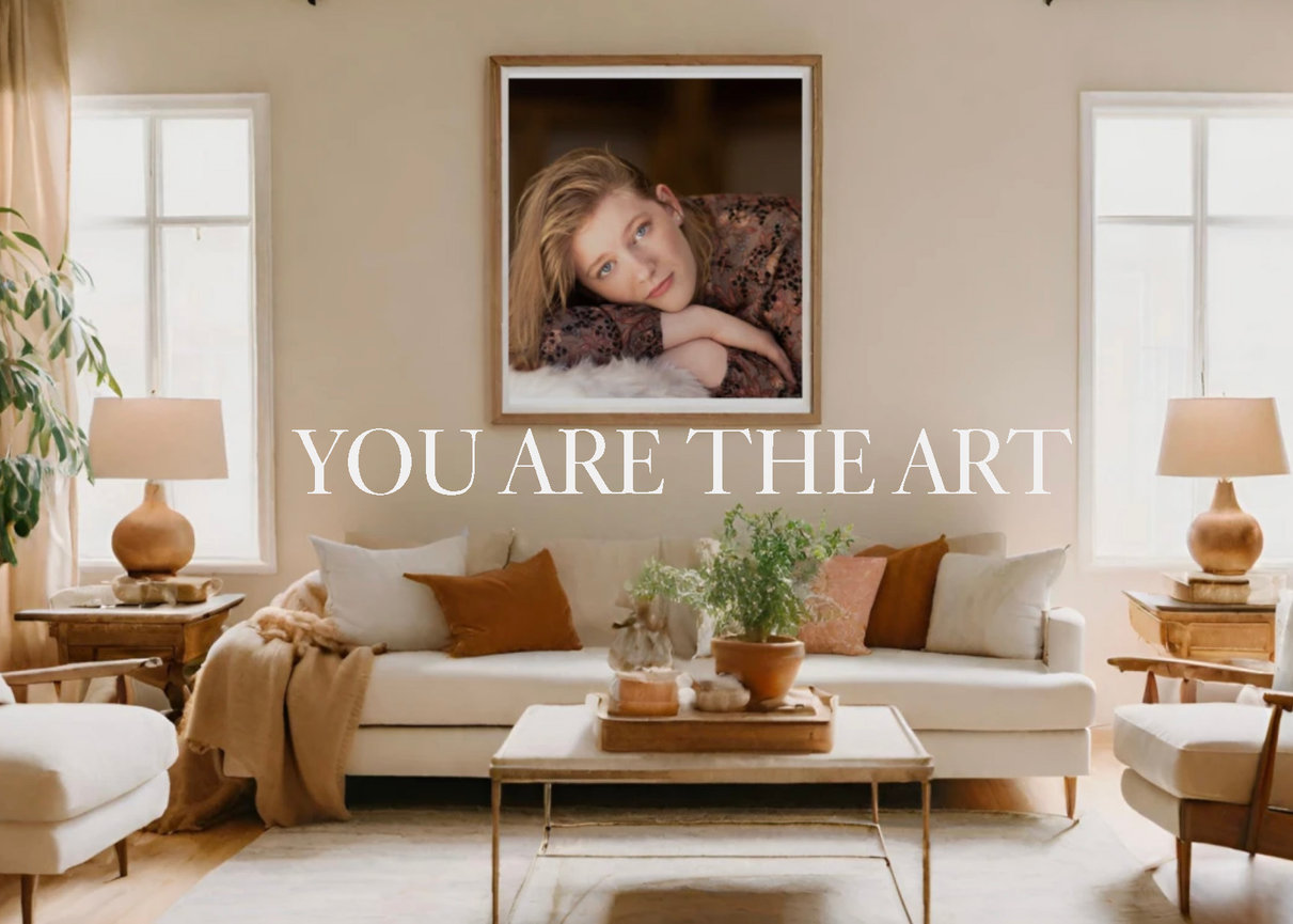 Living room with a large framed portrait above a sofa, plants on a coffee table, and text You Are The Art.