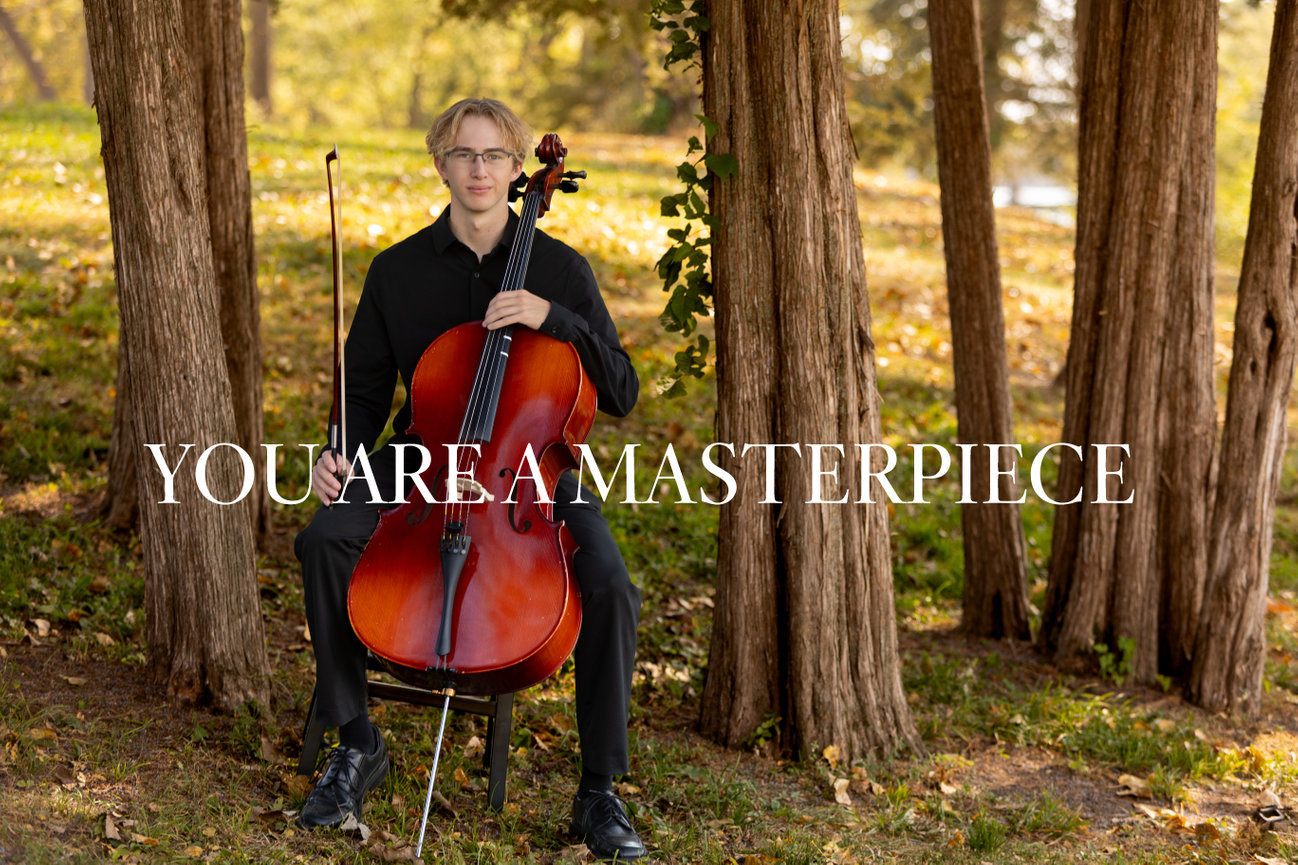 Person seated outdoors playing the cello, surrounded by trees with the text You are a masterpiece overlayed.