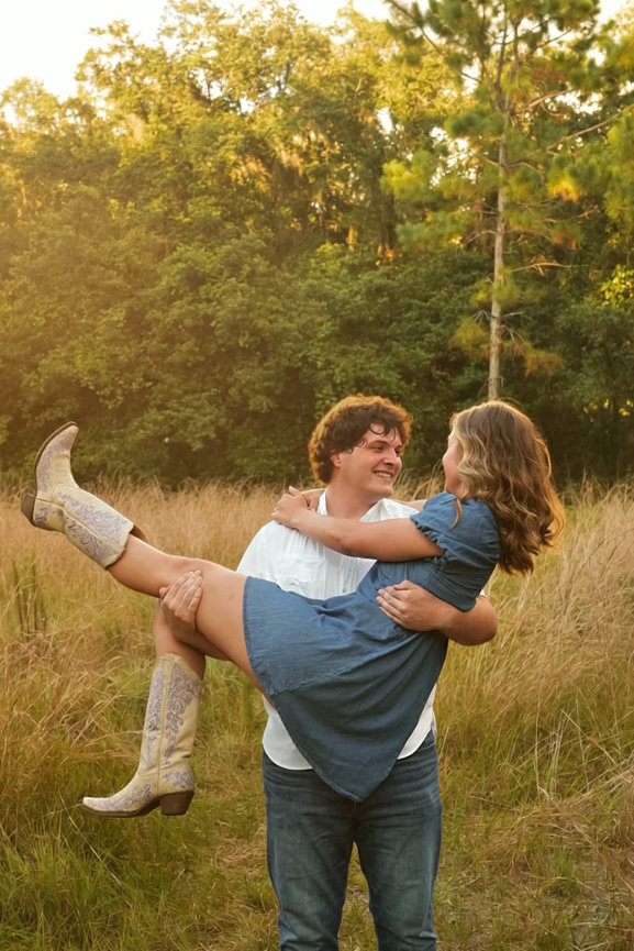 Groom lifting the bride outdoors during golden hour.