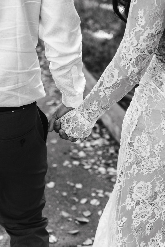 Close up of couple holding hands with lace details