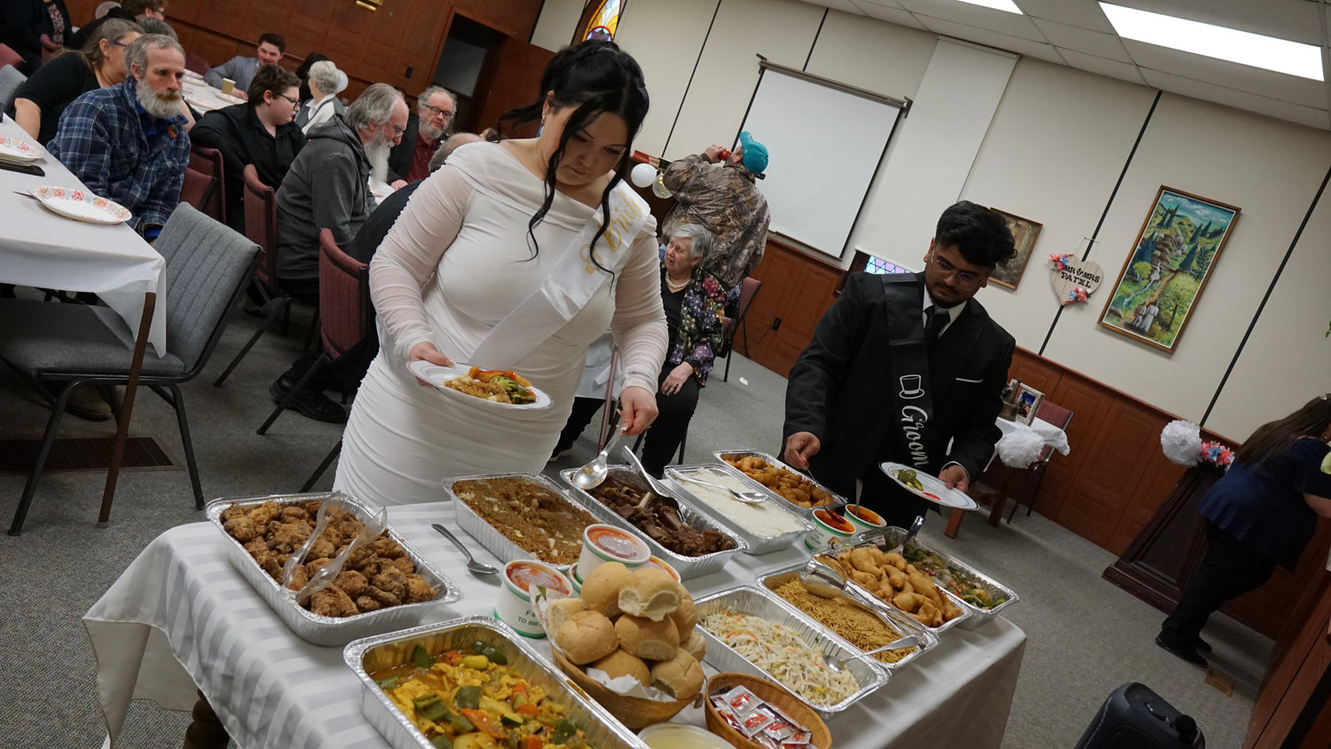 Bride and groom serving themselves at a buffet during the wedding reception