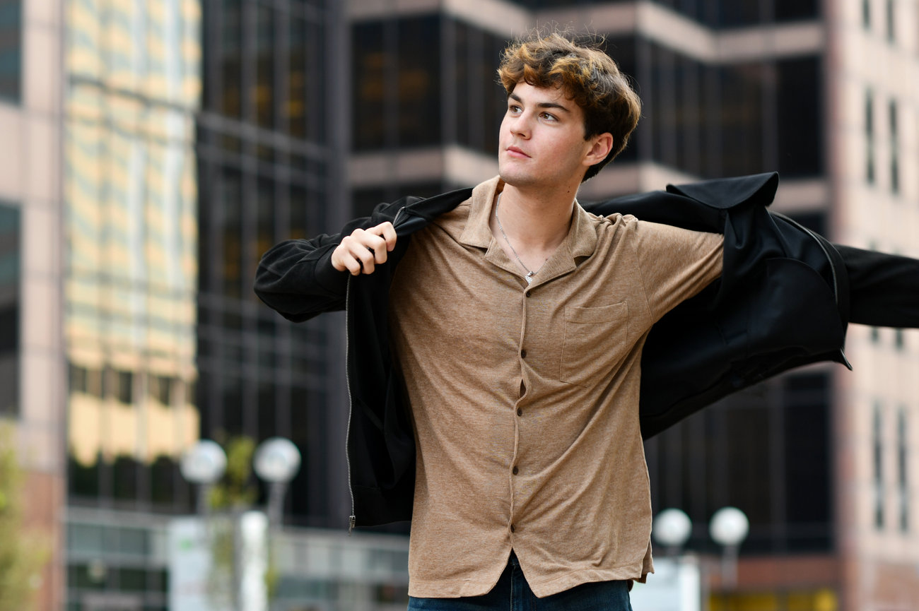 Teenage boy with a black jacket in an urban setting taking senior pictures in Columbus OH.