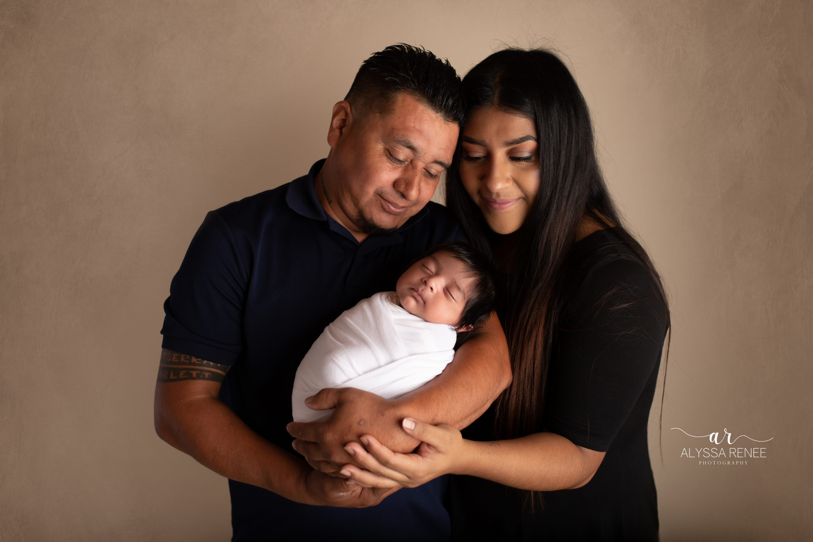 Mommy and Daddy portrait with their newborn on brown background